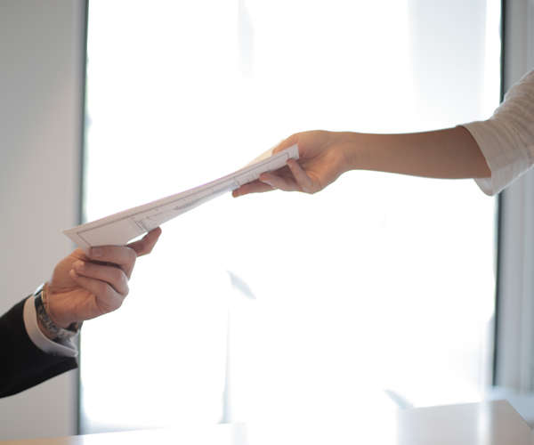 paper documents being handed from one person to another