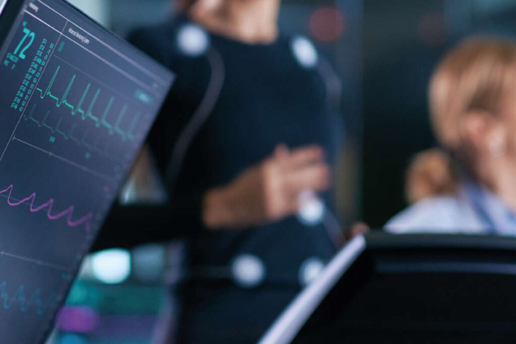 a person being monitored while doing exercise, their heart rate is visible on a monitor