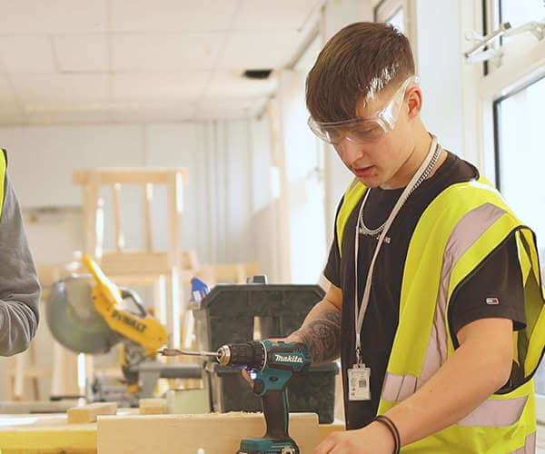 Young man working in a workshop with a drill on the desk