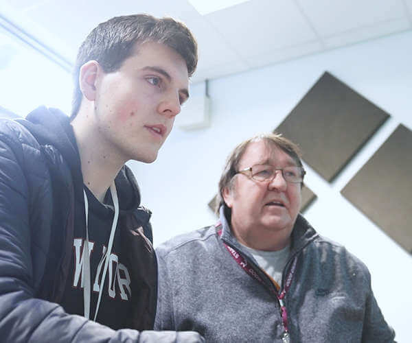 A student with a teacher working on a computer