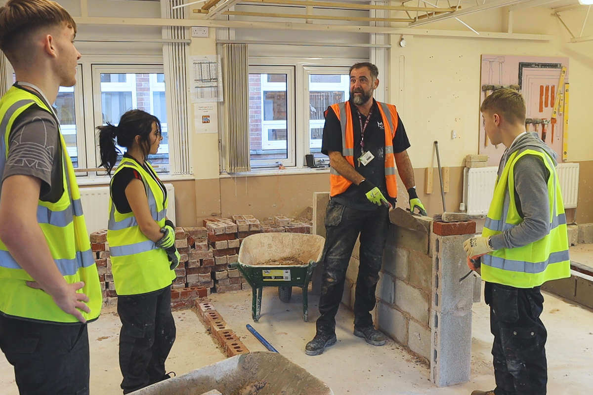 Students watch a demonstration of a wall being built